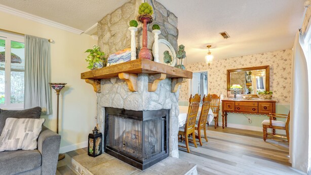 A living room with a stone fireplace, a sofa, and a dining area with wooden chairs and a table. - Wilmington Getaway Near Carolina Beach Boardwalk! (Wilmington)