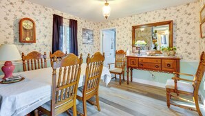 A dining room with a wooden table, chairs, a clock, and a dresser with a mirror. - Wilmington Getaway Near Carolina Beach Boardwalk! (Wilmington)