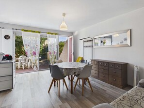 A dining area with a table and chairs, a sofa, a dresser, and a mirror. - Cozy 2-Room Apartment with Terrace, BBQ, and Private Parking in Marseillan (Marseillan-Plage)
