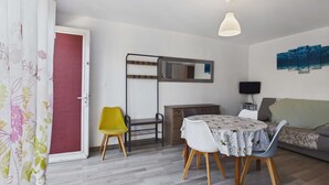 Ein kompakter Wohnraum mit Essbereich, einer Couch, einem Fernseher und einem Gemälde an der Wand.