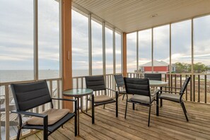 A covered outdoor seating area with a view of the water, featuring several chairs and a table. - Serenity By The Sea - 317 Audubon 5 Bedroom Home by RedAwning (Dauphin Island)