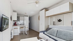 A modern living room with a grey sofa, a small white table, and a remote control on it. - Grau d'Agde: Studio cabin with terrace, private parking, sea view (Le Grau d'Agde)