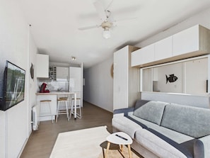 A modern living room with a grey sofa, a small white table, and a remote control on it.