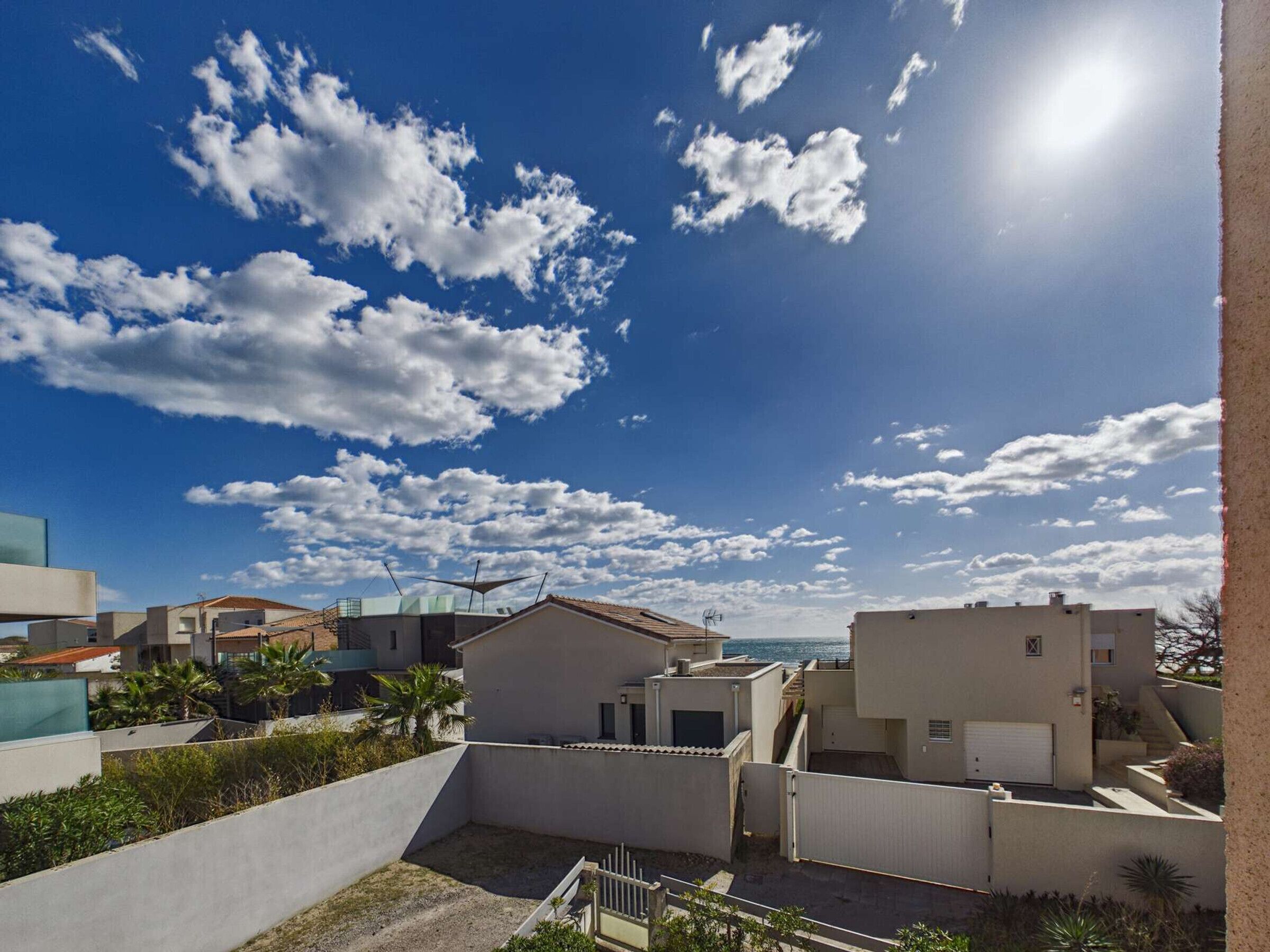 Un quartier résidentiel avec des immeubles modernes, un ciel dégagé et une vue sur la mer.