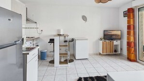 Una cucina compatta con frigorifero, fornello e zona pranzo con tavolo e sedie.