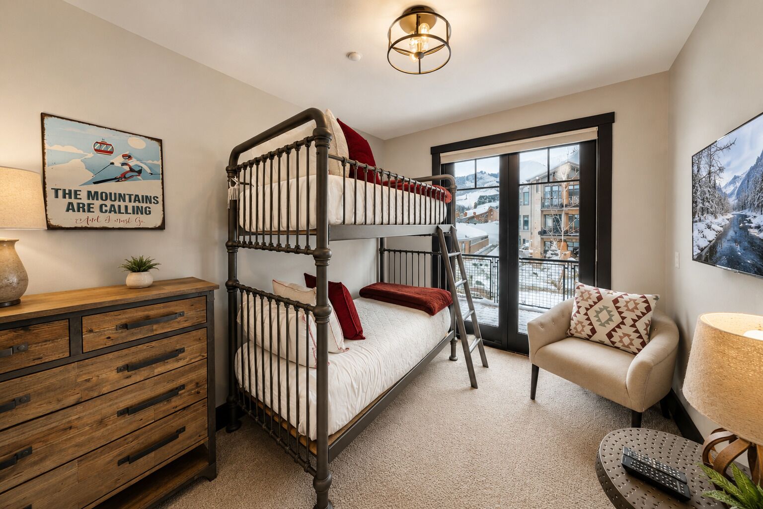 Une chambre avec un lit superposé, une commode en bois, une chaise, une lampe et une grande fenêtre donnant sur des immeubles.
