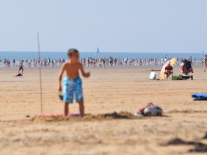 A beach scene with people, a lifeguard tower, and beach equipment.