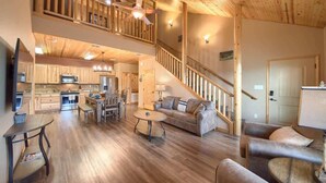 A spacious loft-style living area with a kitchen, dining table, sofa, and staircase.