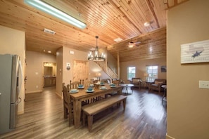 A spacious interior with a wooden dining table, benches, a staircase, and a kitchen area. - OM A6A8 Gruene Road Hideaway at Old Mills Resort (New Braunfels)
