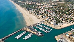 An aerial view of a coastal town with a marina, sandy beach, and residential areas. - Duplex 3-room Apartment, 150m from Beach, Private Parking, Terrace (Marseillan-Plage)