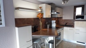 A modern kitchen with white cabinets, a stainless steel countertop, a coffee maker, and a microwave. - Duplex 3-room Apartment, 150m from Beach, Private Parking, Terrace (Marseillan-Plage)
