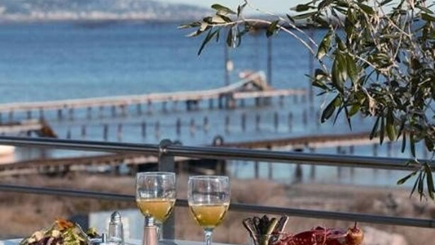 A table with a meal, two glasses of wine, and a view of the sea and a pier. - Duplex 3-room Apartment, 150m from Beach, Private Parking, Terrace (Marseillan-Plage)