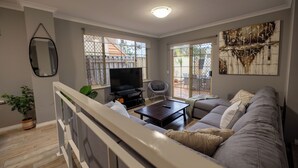 Un salon avec un canapé gris, un téléviseur et une table basse.