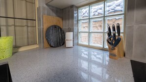 Une cuisine dotée d’un plan de travail en granit, d’une planche à découper en bois, d’un range-couteaux et d’une fenêtre ornée de panneaux de verre décoratifs.