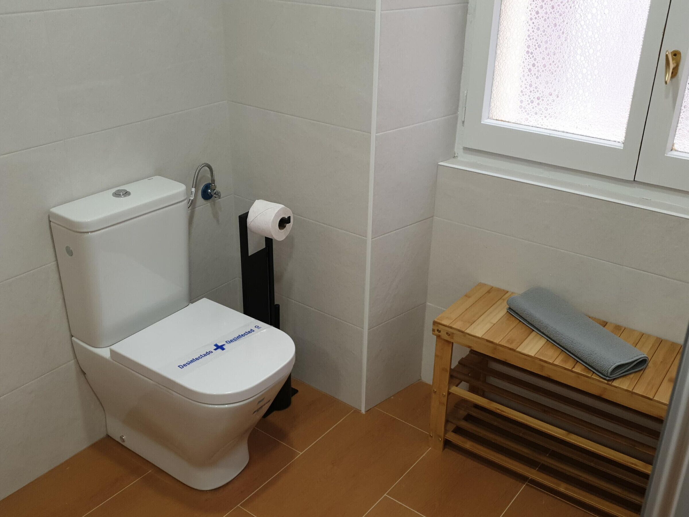 Une petite salle de bain avec des toilettes, un porte-serviettes et une fenêtre.