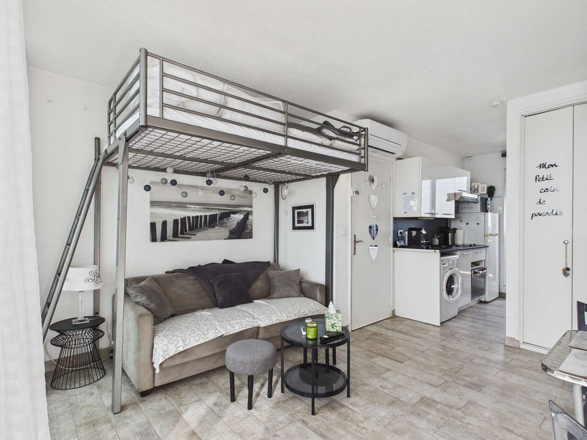 A compact studio apartment with a bunk bed, kitchenette, and a small dining area.
