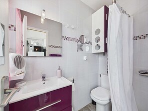 A bathroom with a white sink, purple vanity, a mirror, a toilet, and a shower curtain.
