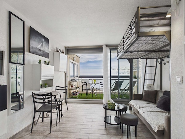 A compact living space with a balcony, a dining area, and a sofa.