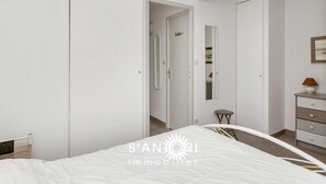 Une chambre à coucher moderne avec un lit, une armoire, un miroir et une commode.