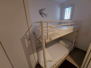 Ein Schlafzimmer mit Etagenbett, Fenster, Wanddekoration und Tür.
