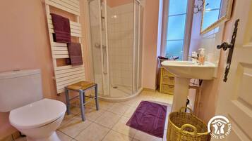 A bathroom with a toilet, a shower, a sink, and a window.