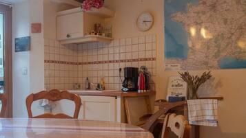 Una cocina con un mapa de Francia, un reloj y una cafetera.