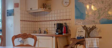 A kitchen with a map of France, a clock, and a coffee maker.