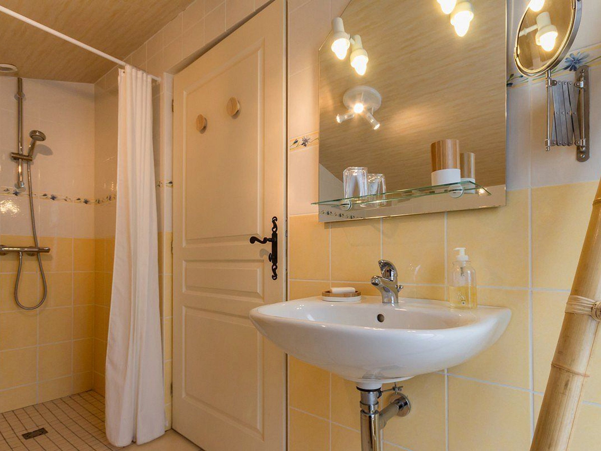 Un baño con lavamanos blanco, espejo y ducha.
