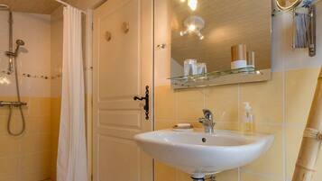 Un baño con lavamanos blanco, espejo y ducha.