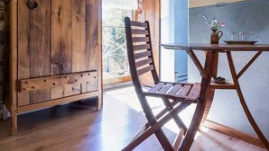 A wooden dining table with a chair, a vase with flowers, and a view of the outdoors. - Rustic Getaway: Cozy Room, Private Bath, Breakfast, and Family Friendly in Bouvron (Bouvron)