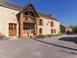 A stone building with a wooden balcony, a door, and windows with shutters. - Rustic Getaway: Cozy Room, Private Bath, Breakfast, and Family Friendly in Bouvron (Bouvron)