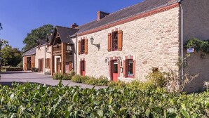 A stone building with red shutters and a small porch. - Rustic Getaway: Cozy Room, Private Bath, Breakfast, and Family Friendly in Bouvron (Bouvron)