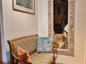 Una habitación con un sofá estampado, un espejo con un marco ornamentado y un cuadro en la pared.