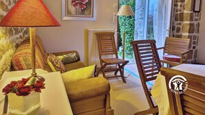 Una sala de estar acogedora con un sofá, sillas, una mesa y un jarrón de flores.