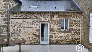Un edificio de piedra con un patio empedrado, una puerta y una ventana.