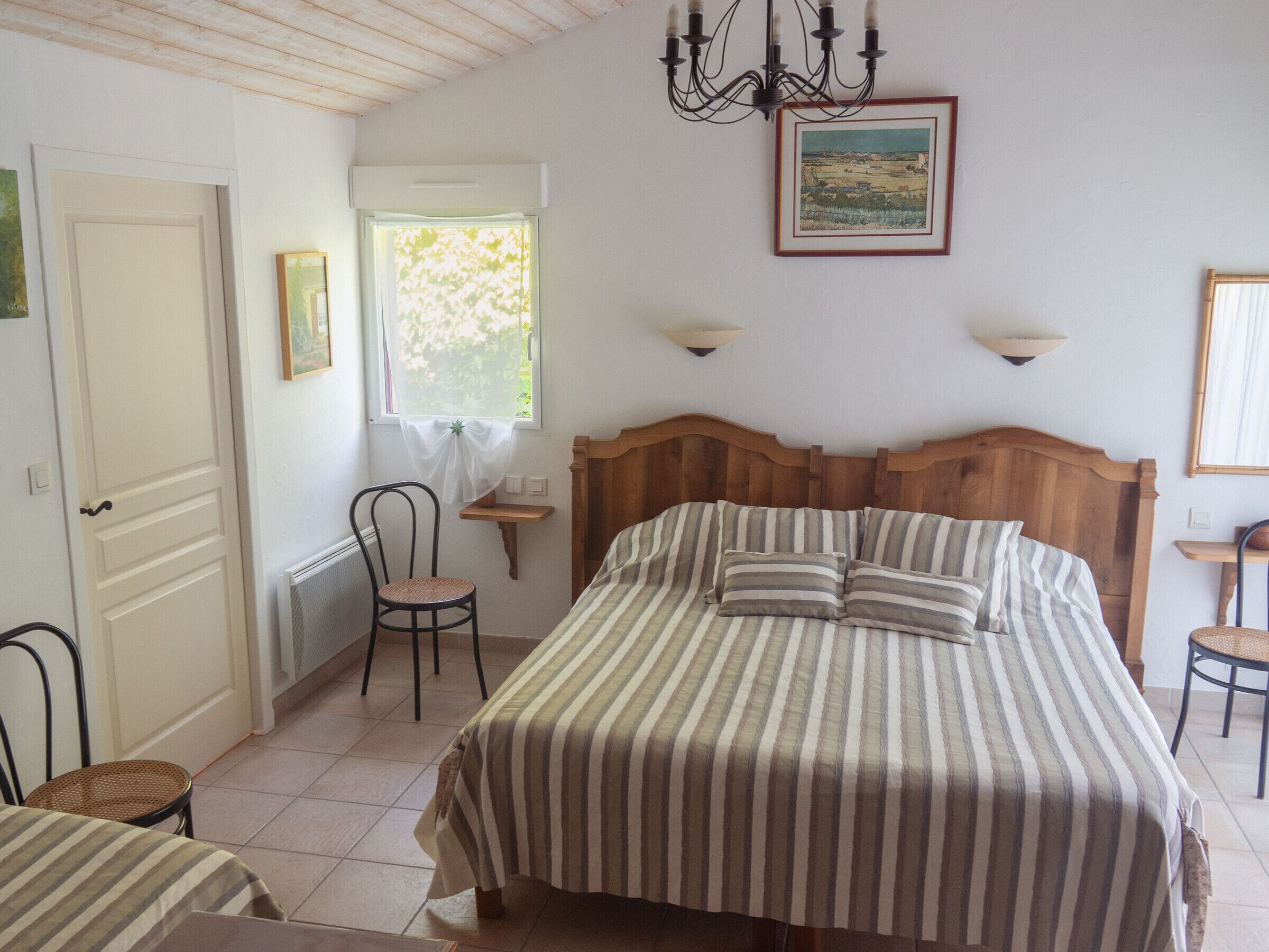 Une chambre à coucher avec un lit, une chaise, une fenêtre et un tableau au mur.