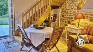 Una habitación acogedora con una escalera de madera, una mesa de comedor con sillas, un sofá y una lámpara.