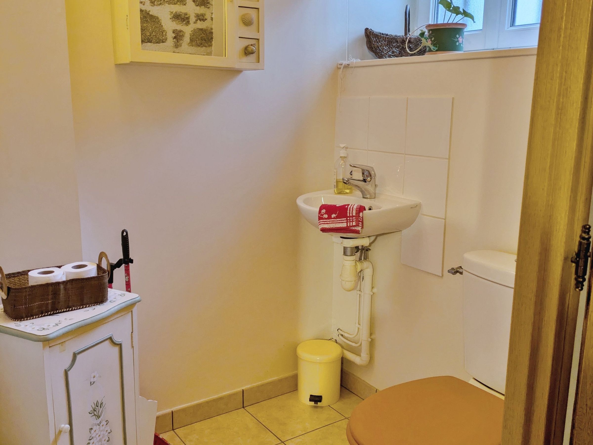 Un baño pequeño con lavamanos, inodoro y un armario con artículos de tocador.