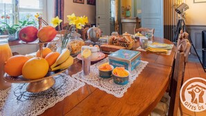 Una mesa de desayuno con frutas, pan y una tetera.