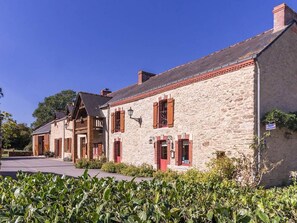 Een stenen gebouw met rode luiken en een klein portaaltje.