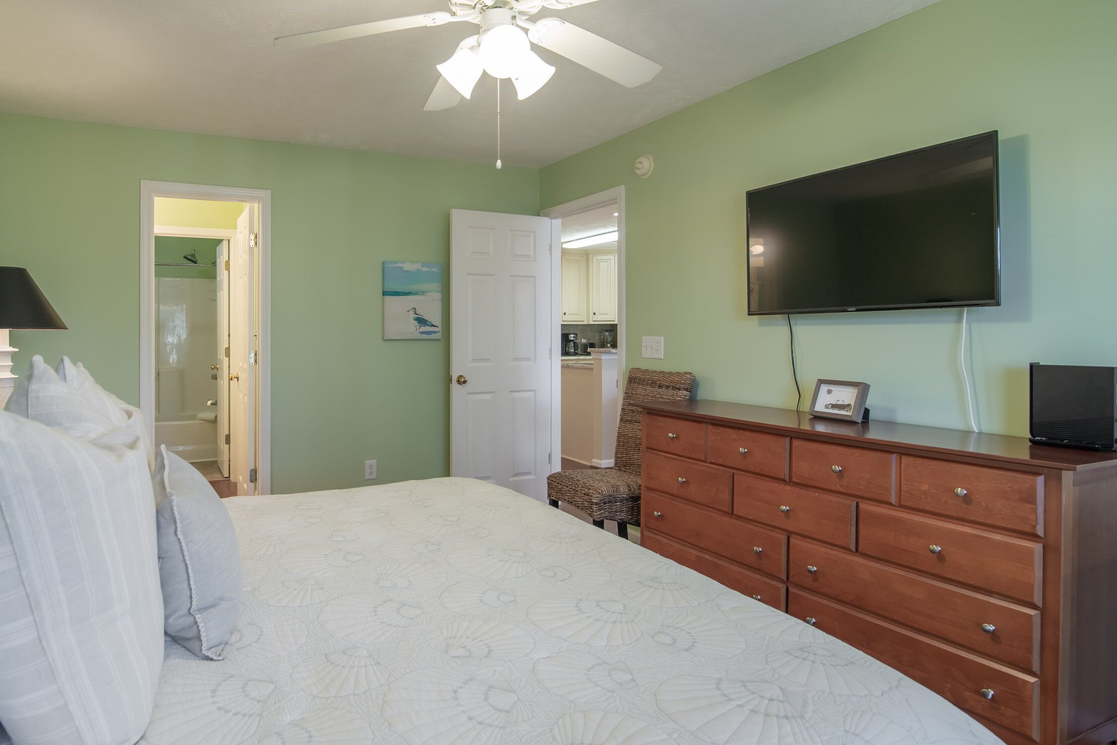 Une chambre à coucher comprenant un lit, une commode, un téléviseur et une porte donnant accès à une salle de bain.