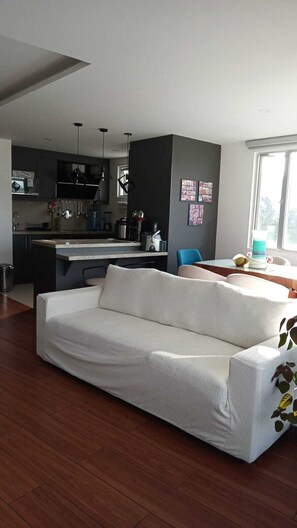 Un salon moderne comprenant un canapé, une table à manger et un coin cuisine.