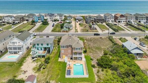 A coastal residential area with houses, a swimming pool, and a beach in the background. - The Beachcomber - Nags Head MP 12, 125 Yds to Beach, Ocean View, Elevator, Pool, Hot Tub (Nags Head)