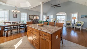 A spacious kitchen with a large island, wooden cabinets, and a ceiling fan. - The Beachcomber - Nags Head MP 12, 125 Yds to Beach, Ocean View, Elevator, Pool, Hot Tub (Nags Head)