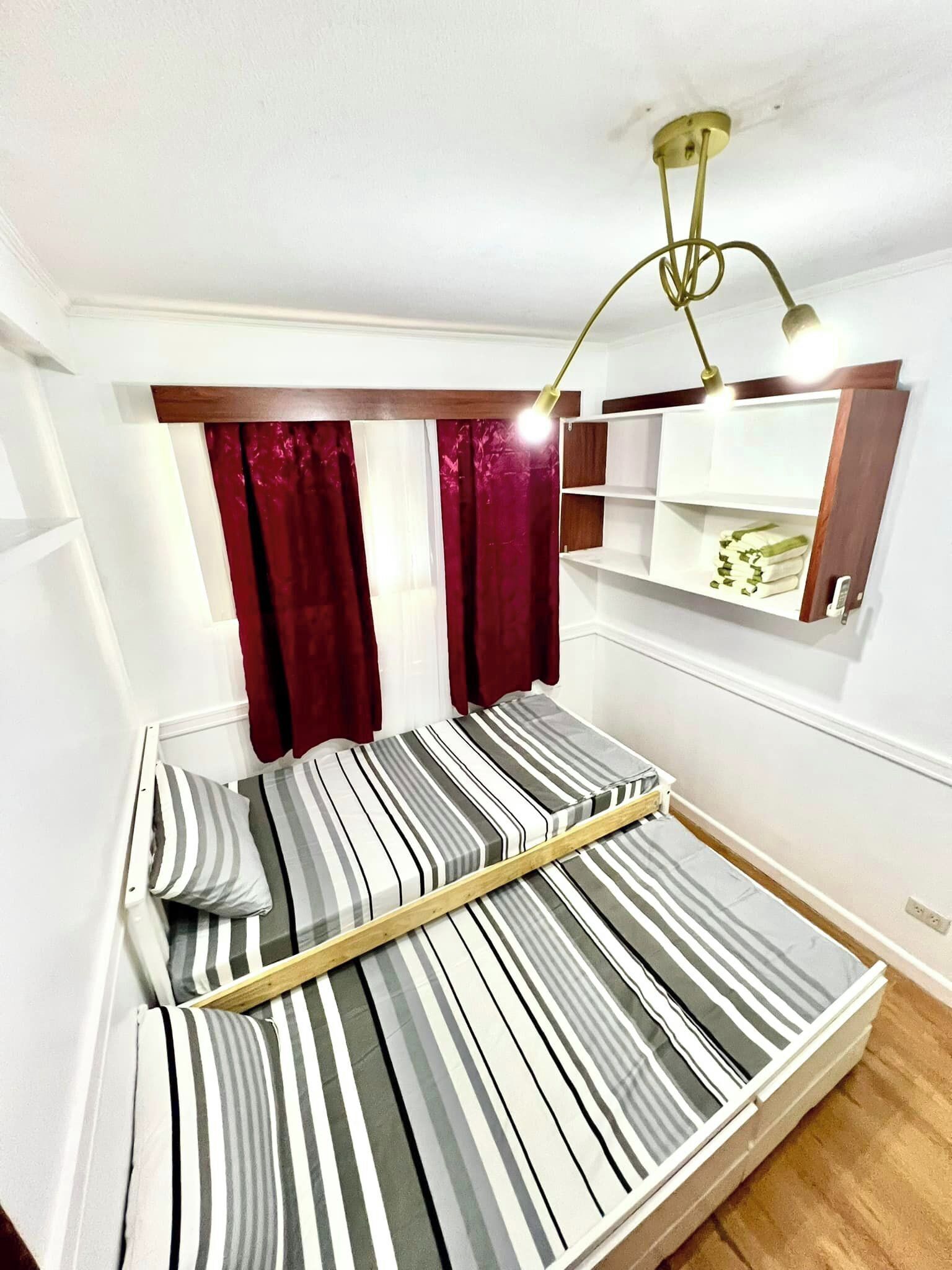 Un lit simple avec une literie à rayures, une tête de lit en bois et une étagère de chevet avec une lampe.