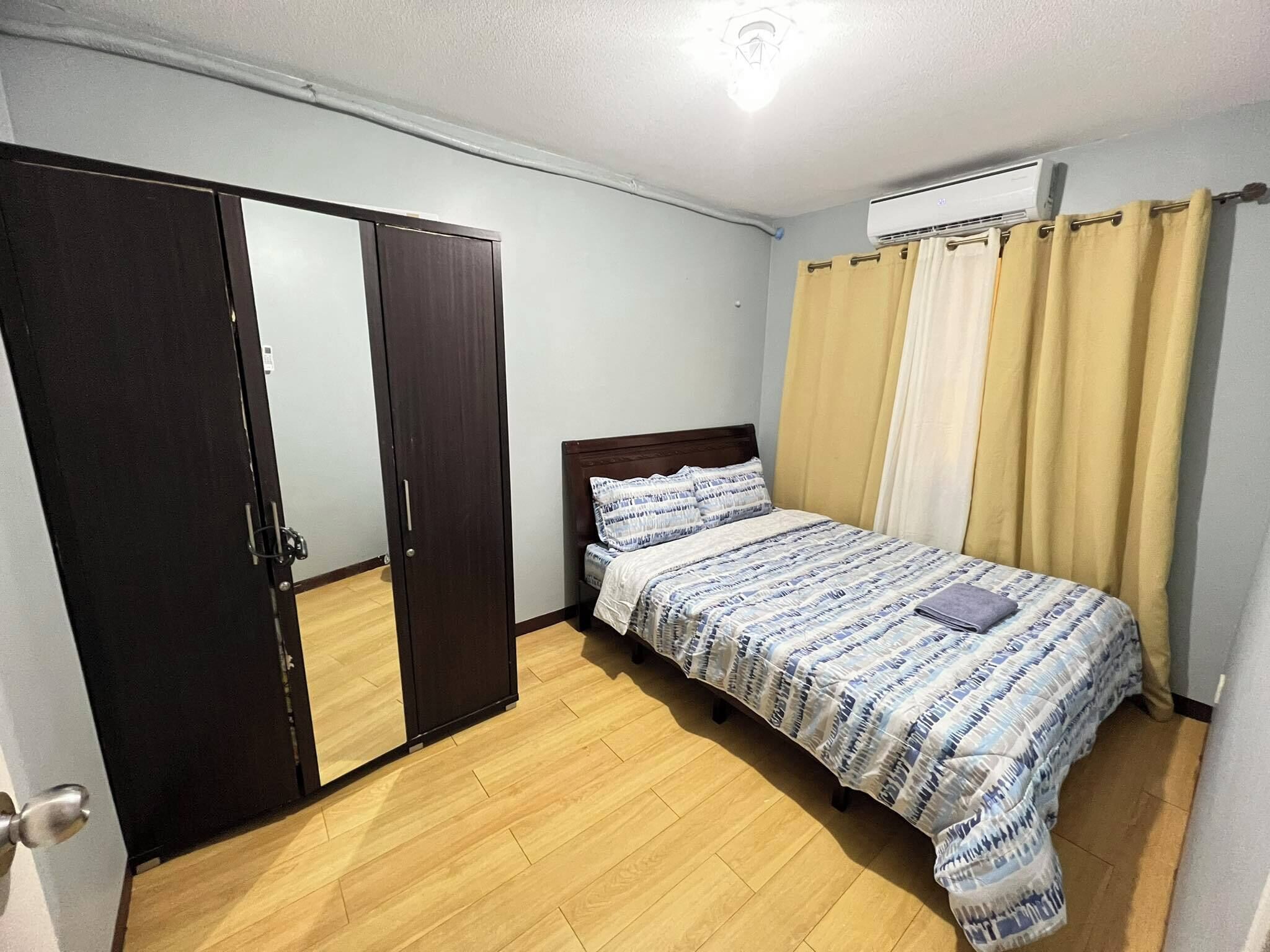 Een slaapkamer met een bed, een kledingkast en een airconditioning.