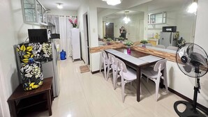 A modern kitchen with a dining area, white cabinets, a large mirror, and a fan. - One Oasis Condo 2 BR Near SM City Davao (Davao)