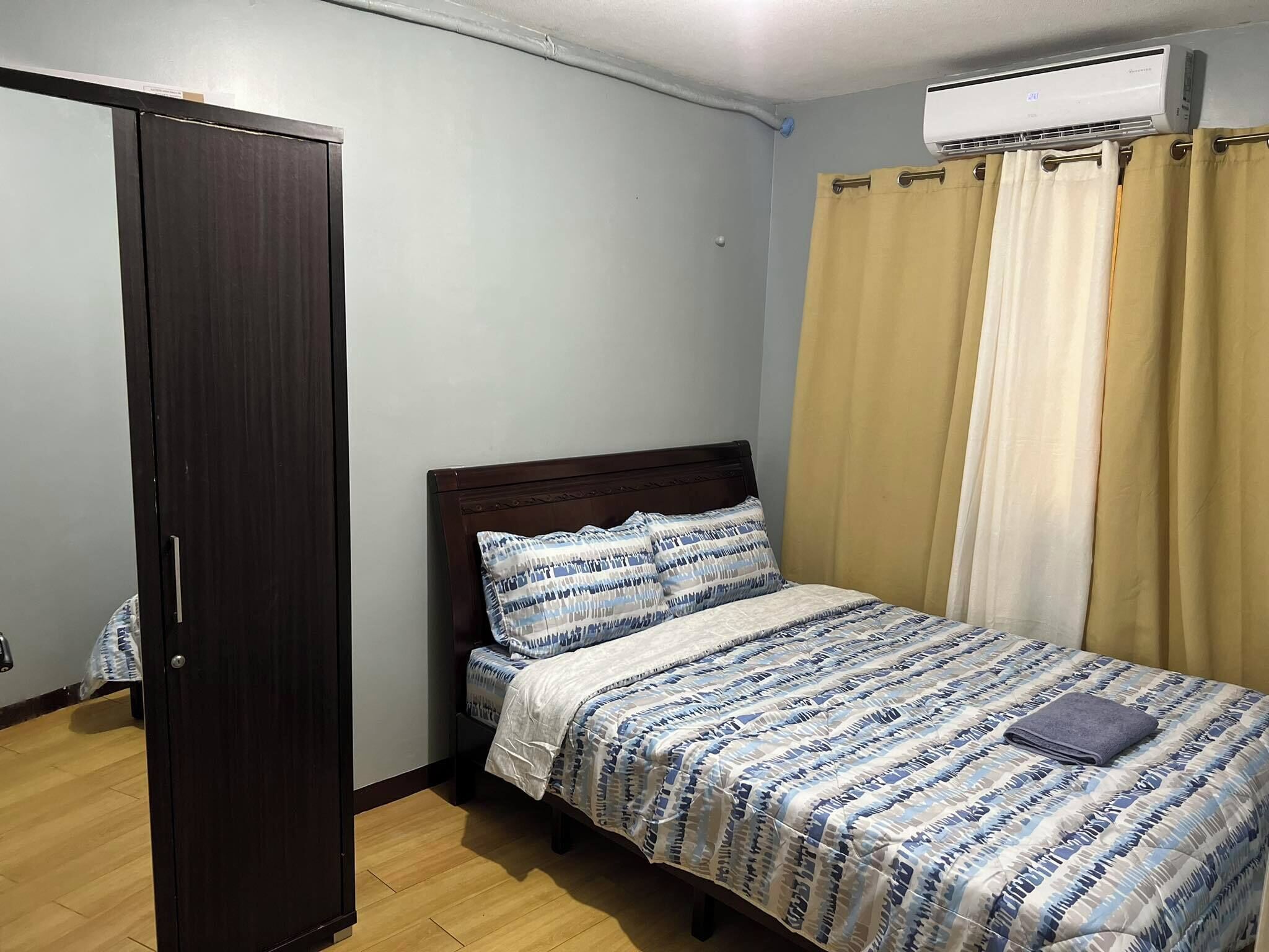 Un dormitorio con cama, armario y equipo de aire acondicionado.