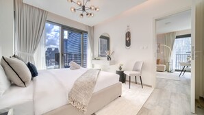 Une chambre d’hôtel moderne avec un grand lit, une coiffeuse, une chaise et une vue sur la ville.