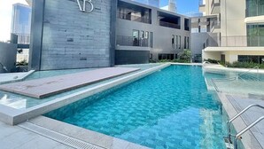 Un bâtiment moderne doté d’un espace piscine et arborant un logo bien visible sur sa façade.